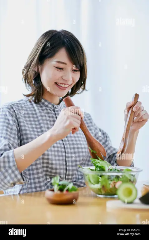 Seorang wanita sedang menikmati salad buah yang berisi pepaya Jepang