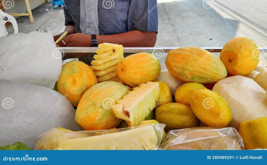 Seorang pedagang kaki lima yang ramah sedang menjual rujak pepaya muda.