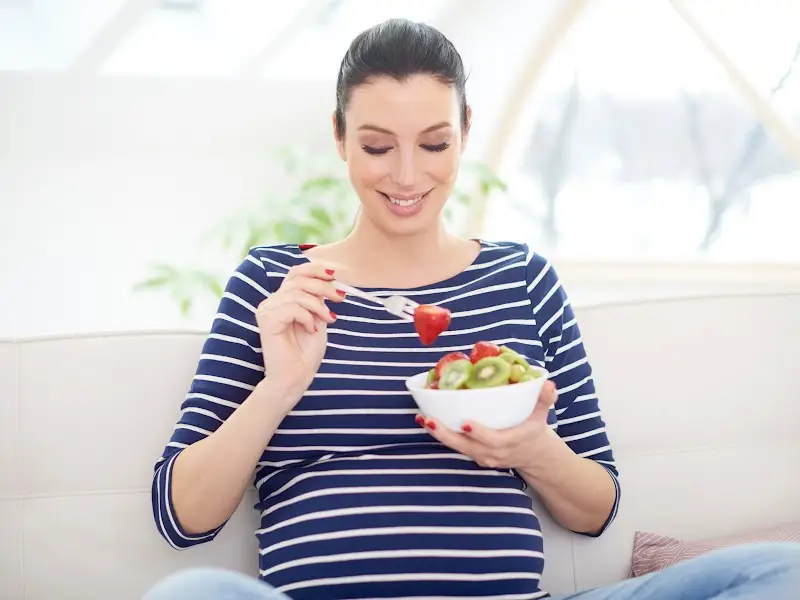 Ibu hamil sedang makan salad pepaya